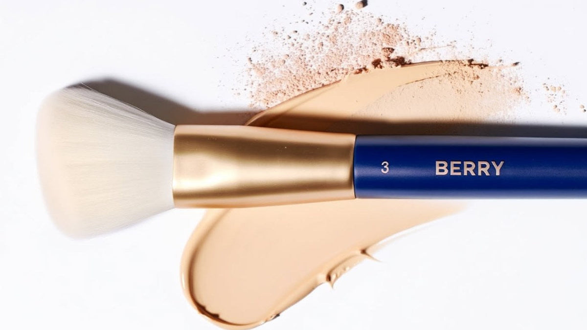 BERRY GOODS bronzer brush number three resting on a swatch of loose powder and liquid foundation